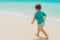 Little kid running on sandy beach near sea
