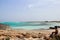 Little kid sitting close to sea shore in Ses Illetes beach, one of the most amazing and iconic spots of Formentera island, Spain