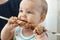 Little kid takes dad`s fried meat kebab, barbecue. The first time the baby tastes meat. Harmful food for children.