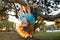 Little kid on a tree branch. Climbing and hanging child. Portrait of a beautiful kid in park among trees. Extreme kid