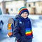 Little kids boy of elementary class walking to school during snowfall. Happy child having fun and playing with first