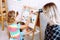 Little kids and educator playing and studying numbers and alphabet on magnetic board sitting on floor in playroom