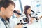 Little kids learning chemistry in school laboratory looking in microscopes