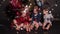 Little kids sitting on floor with colorful balloons behind.