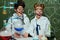 Little kids in white coats with chalkboard behind in science laboratory