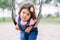 Little latin hispanic toddler girl swinging on swings at playground outside on summer day