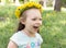 Little laugh girl with dandelions wreath on her head smell dandelion