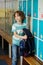 Little learner standing near lockers in school hallway