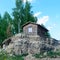 Little lone taiga house of timber with a window stands on the hill at the cliff in the woods.