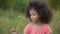 Little lonesome kid standing in garden and playing with small white flower