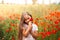 Little longhaired girl  posing at field of poppies with  on summer sun