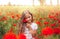 Little longhaired girl  posing at field of poppies with  on summer sun