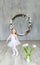 Little lovely ballerina in white dress and tulips is posing in a beautiful studio.