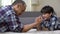 Little male kid challenging his father in arm wrestling, having fun together