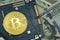 A little miner is digging for bitcoin with graphic card dollars. Golden Bitcoin on the blue microchip board with dollars