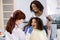 Little mixed raced school girl with curly hair, visiting dentist for checkup or caries treatment, sitting in dental