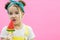 Little model is licking a lollipop. Pink background