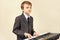 Little musician in suit playing the digital piano