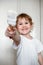 A little naughty girl in a white t-shirt paints the wall with white paint. reaching into the camera with a brush