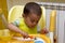 Little one-year-old kid eats porridge while sitting in his high chair