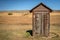 Little outhouse on the prairie made of wood on the edge of a fie