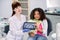 Little patient kid mixed raced girl with curly hair, sitting in dentistry chair and showing tablet with teeth panoramic