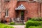 Little patio with iron railings on brick house - Stiped awning over door with wreath and chiminea and white iron bistro set -