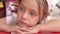 Little pensive girl at a red table