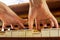 Little pianist diligently learns an exercise on the piano with both hands, view from below. music lesson