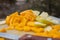 Little pile of mango and apple slices with blurry trees as background