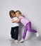 Little positive baby girl and boy in stylish casual clothing standing, hugging each other, playing and smiling