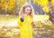 Little positive child having fun outdoors in autumn park