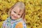 Little positive girl 5 years old, blonde, smiling cheerfully, portrait against a background of brightly blossoming yellow flowers