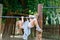 Little preschool girl climbing and hanging on outdoor horizontal bar. Cheerful girl athlete on gymnastic stick on sports