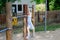 Little preschool girl climbing and hanging on outdoor horizontal bar. Cheerful girl athlete on gymnastic stick on sports