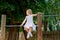 Little preschool girl climbing and hanging on outdoor horizontal bar. Cheerful girl athlete on gymnastic stick on sports