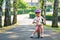 Little preschool girl with helmet running with balance bike on summer day. Happy child driving, biking with bicycle