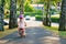 Little preschool girl with helmet running with balance bike on summer day. Happy child driving, biking with bicycle
