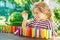 Little preschool girl playing board game with colorful bricks domino. Happy child build tower of wooden blocks