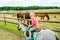 Little preschool girl riding a pony on a farm. Happy lovely child practicing horseback riding. Outdoor summer activities