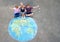 Little preschool girl and two school kids boys with earth globe painting with colorful chalks on ground. Happy earth day