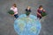 Little preschool girl and two school kids boys with flowers on earth globe painting with colorful chalks on ground