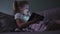 Little preschool girl use digital tablet technology device lying at sofa in dark room. Eyes care, gadget addiction