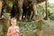 Little pretty girl standing near tamed and tied elephants.