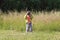 Little pretty girl stands on green grass and shoots