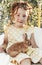 Little pretty girl in summer dress sitting outside with little rabbit