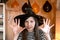 Little pretty girl witch in black wizard hat says Boo with scary gesture. Halloween kids Portrait. Girl in Halloween