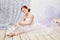 Little prima ballet. Young ballerina girl is preparing for a ballet performance. Girl in a white ball gown and Pointe near the wi