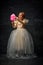 Little princess in old-fashioned dress eating, tasting bright pink sweet cotton candy against dark vintage background