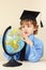 Little professor in academic hat looks at globe